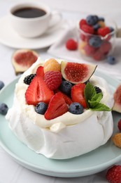 Photo of Pavlova cake (meringue dessert) with whipped cream, fresh berries, mint and fig on table, closeup