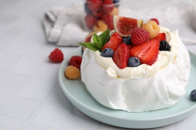 Photo of Pavlova cake (meringue dessert) with whipped cream, fresh berries, mint and fig on white tiled table, closeup