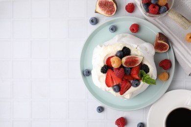 Photo of Pavlova cake (meringue dessert) with whipped cream, fresh berries and fig on white tiled table, flat lay. Space for text