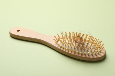 Photo of One brush with lost hair on light olive background. Alopecia problem