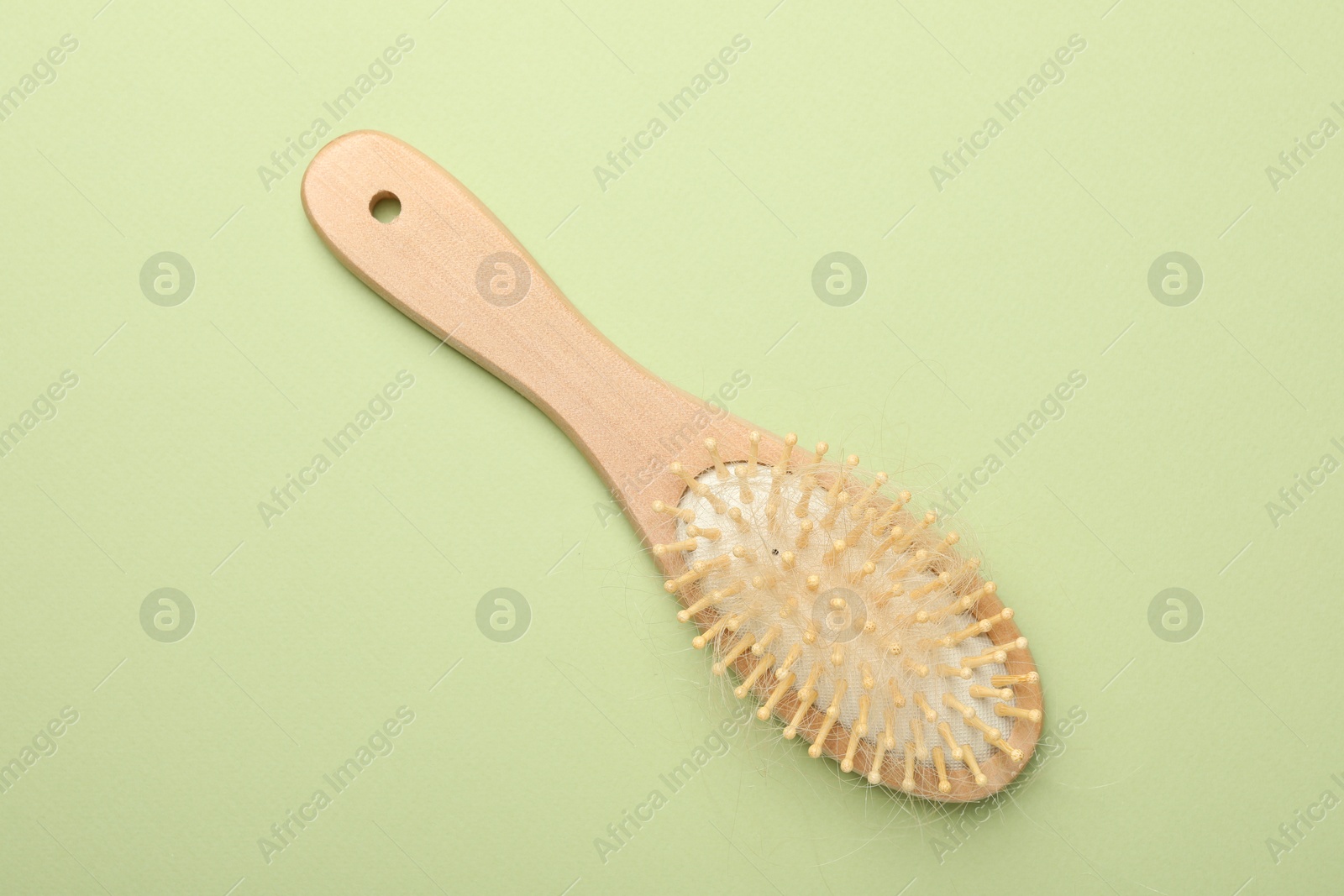 Photo of One brush with lost hair on light olive background, top view