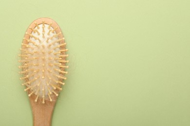 Photo of One brush with lost hair on light olive background, top view. Space for text