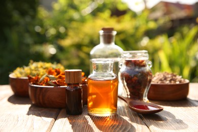 Photo of Different tinctures and ingredients on wooden table outdoors