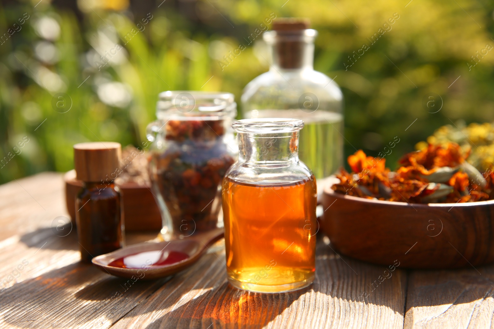 Photo of Different tinctures and ingredients on wooden table outdoors