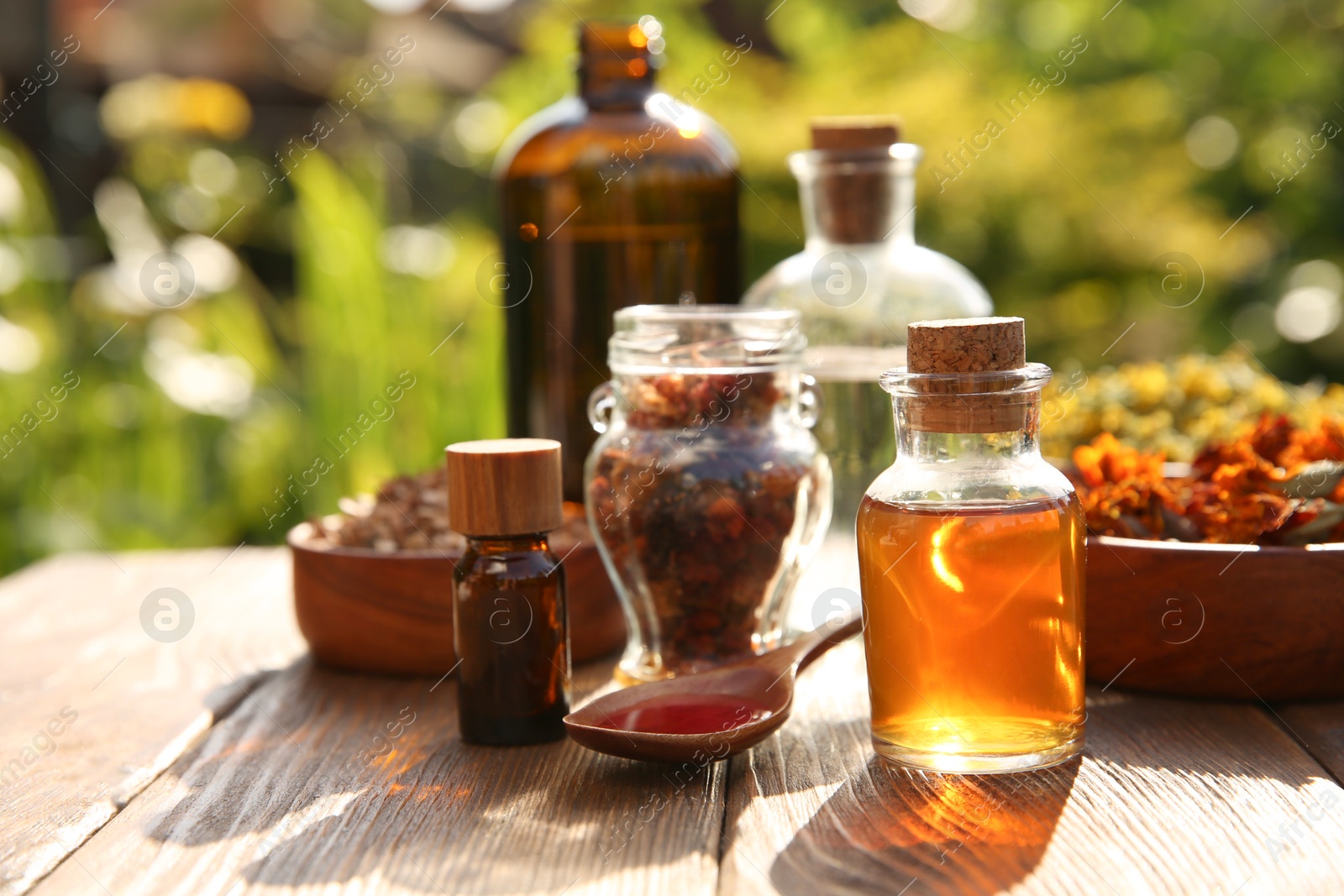 Photo of Different tinctures and ingredients on wooden table outdoors