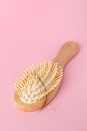 Photo of One brush with lost hair on pink background, closeup