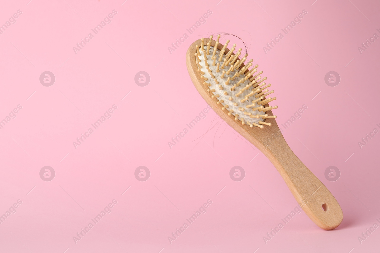 Photo of One brush with lost hair on pink background, closeup. Space for text