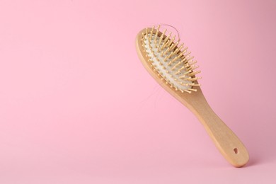 Photo of One brush with lost hair on pink background, closeup. Space for text