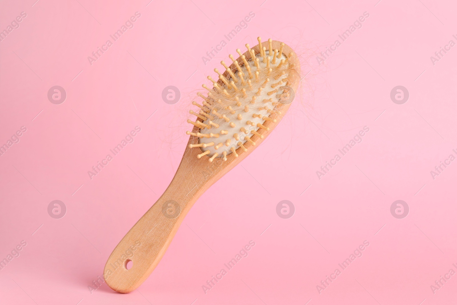 Photo of One brush with lost hair on pink background, closeup. Space for text