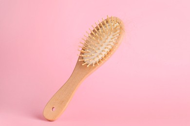 Photo of One brush with lost hair on pink background, closeup. Space for text