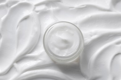 Face cream in jar on cosmetic product, top view