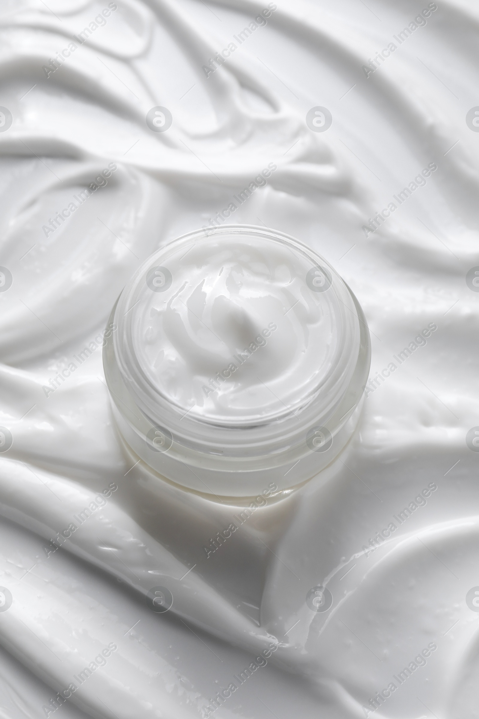 Photo of Face cream in jar on cosmetic product, above view