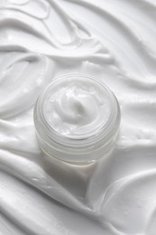 Face cream in jar on cosmetic product, above view