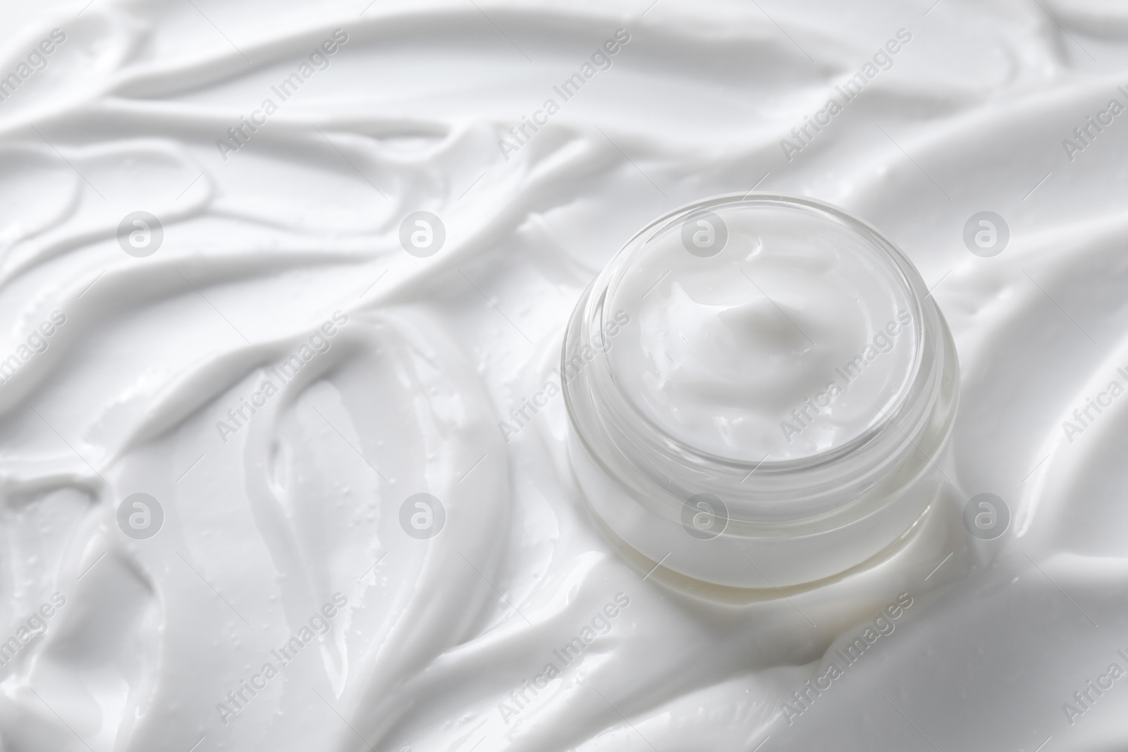 Photo of Face cream in jar on cosmetic product, closeup. Space for text