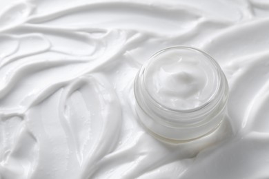 Photo of Face cream in jar on cosmetic product, closeup. Space for text