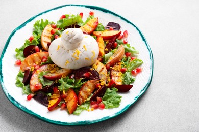 Plate with fresh burrata salad on grey textured table, closeup