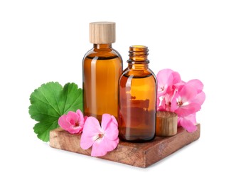 Photo of Geranium essential oil in bottles and beautiful flowers isolated on white