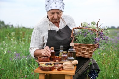 Photo of Senior woman with tincture and different ingredients outdoors