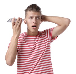 Young man with smartphone listening to voice message on white background