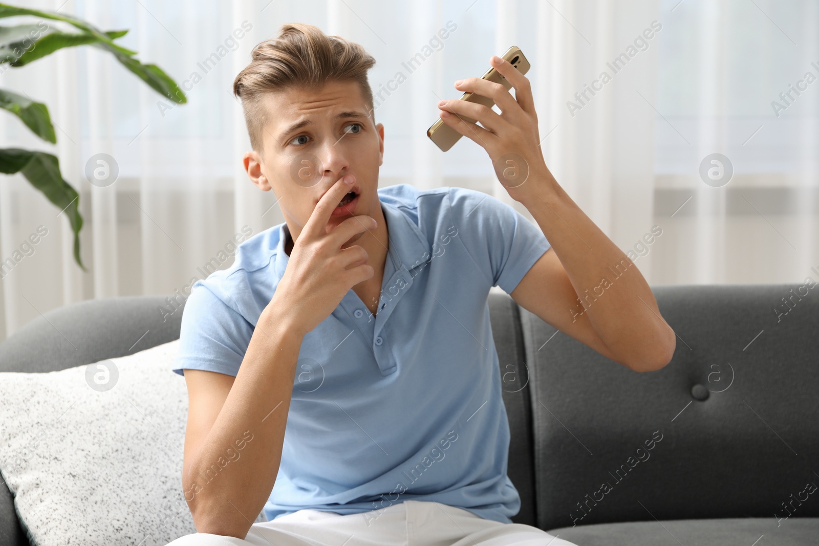 Photo of Young man with smartphone listening to voice message at home