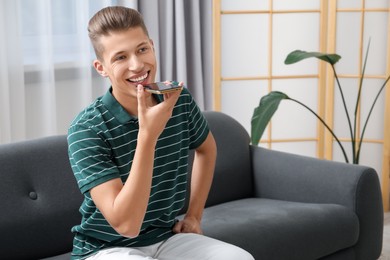 Young man recording voice message via smartphone at home