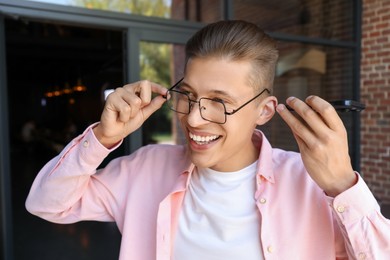 Young man with smartphone listening to voice message outdoors