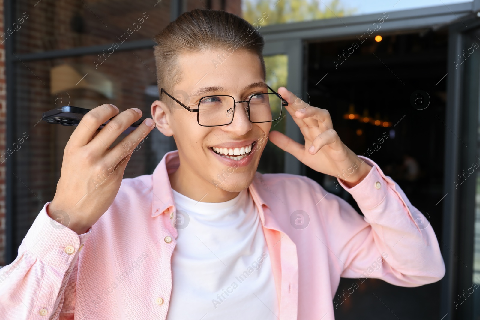 Photo of Young man with smartphone listening to voice message outdoors