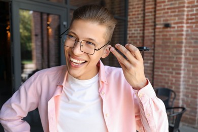 Young man with smartphone listening to voice message outdoors