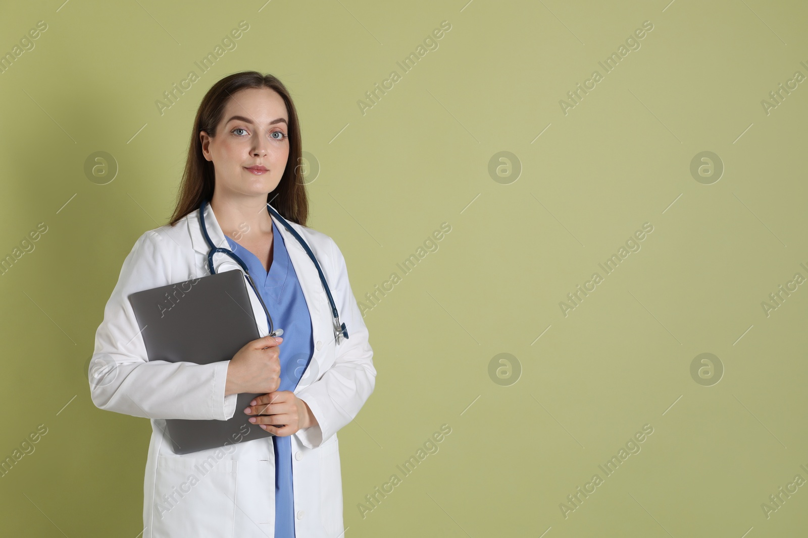 Photo of Professional nurse with laptop and stethoscope on pale green background. Space for text