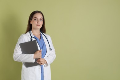 Photo of Professional nurse with laptop and stethoscope on pale green background. Space for text