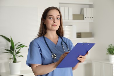 Portrait of professional nurse with clipboard in clinic