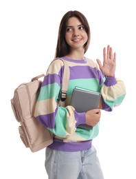 Teenage girl with backpack and book waving hello on white background