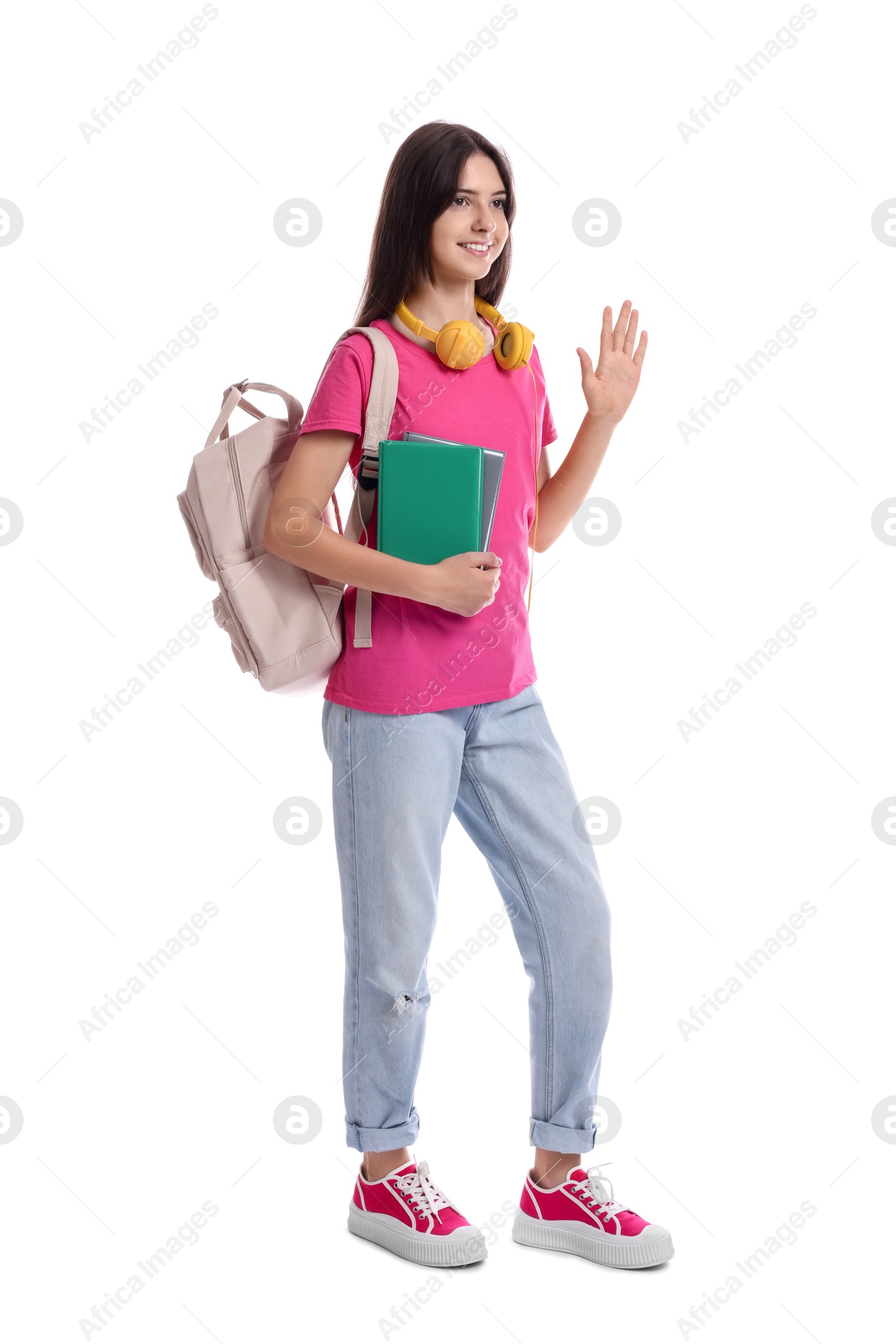 Photo of Teenage girl with backpack and books waving hello on white background