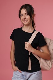 Portrait of cute teenage girl with backpack on pink background