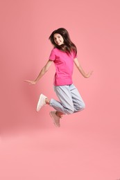 Happy teenage girl jumping on pink background