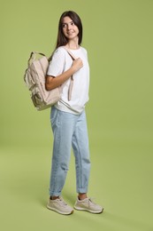 Cute teenage girl with backpack on olive background