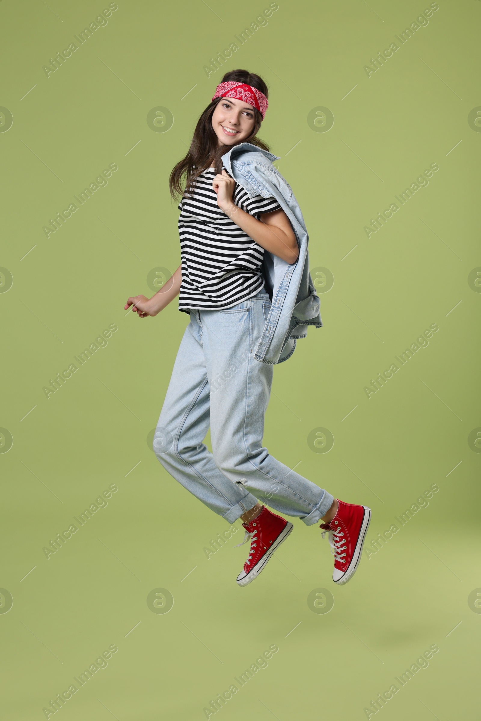 Photo of Cheerful teenage girl jumping on olive background