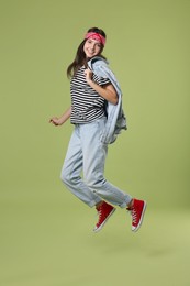 Cheerful teenage girl jumping on olive background