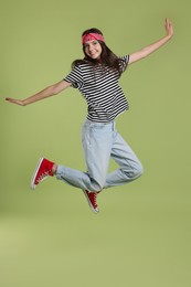 Photo of Cheerful teenage girl jumping on olive background