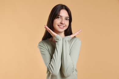 Portrait of cute teenage girl on beige background