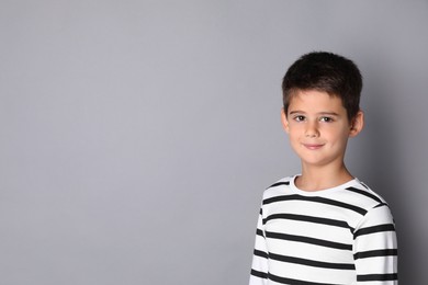 Photo of Portrait of cute little boy on grey background, space for text