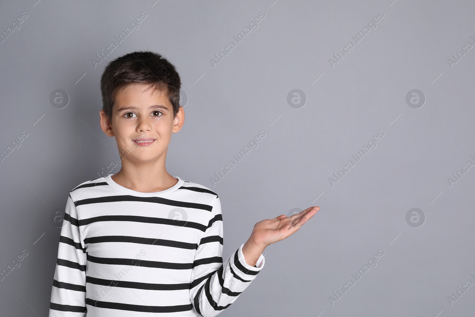 Photo of Portrait of cute little boy on grey background, space for text