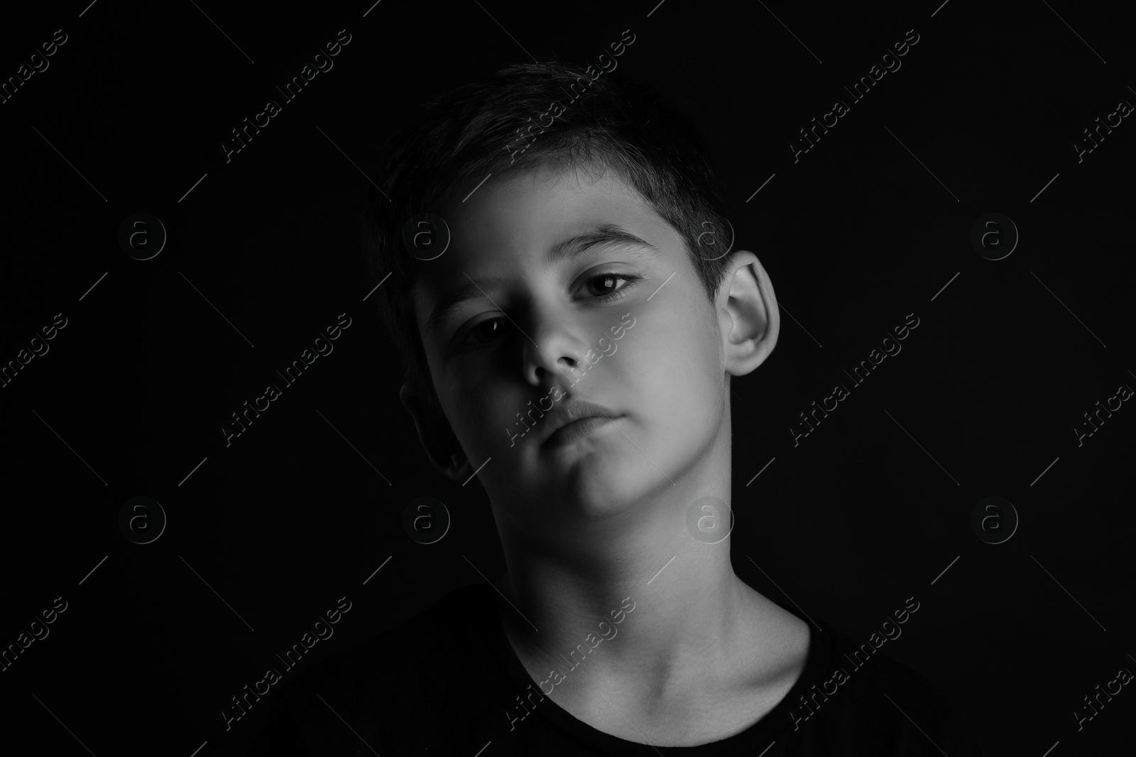 Photo of Portrait of sad little boy on dark background. Black and white effect