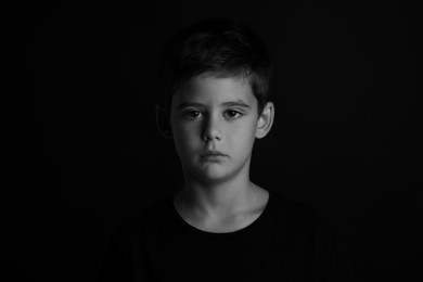 Photo of Portrait of sad little boy on dark background. Black and white effect