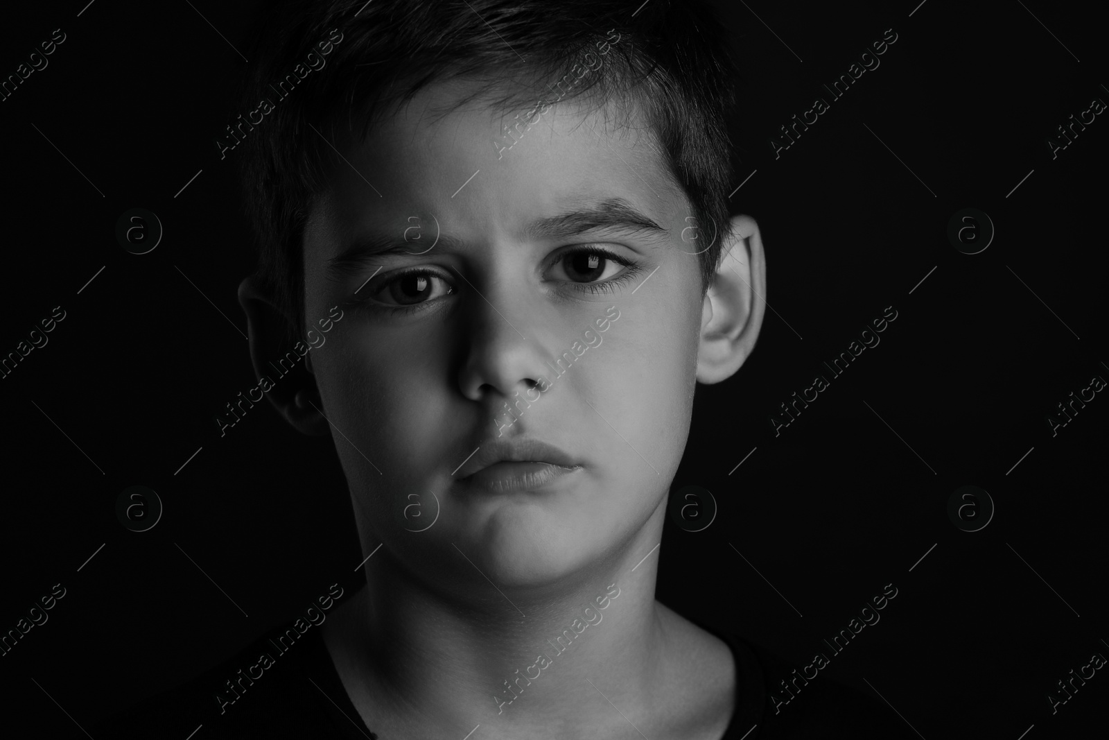 Photo of Portrait of sad little boy on dark background. Black and white effect