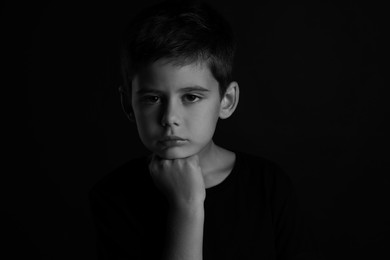 Photo of Portrait of sad little boy on dark background. Black and white effect