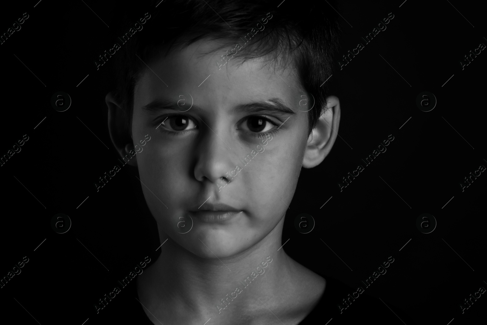 Photo of Portrait of sad little boy on dark background. Black and white effect