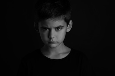 Angry little boy on dark background. Black and white effect