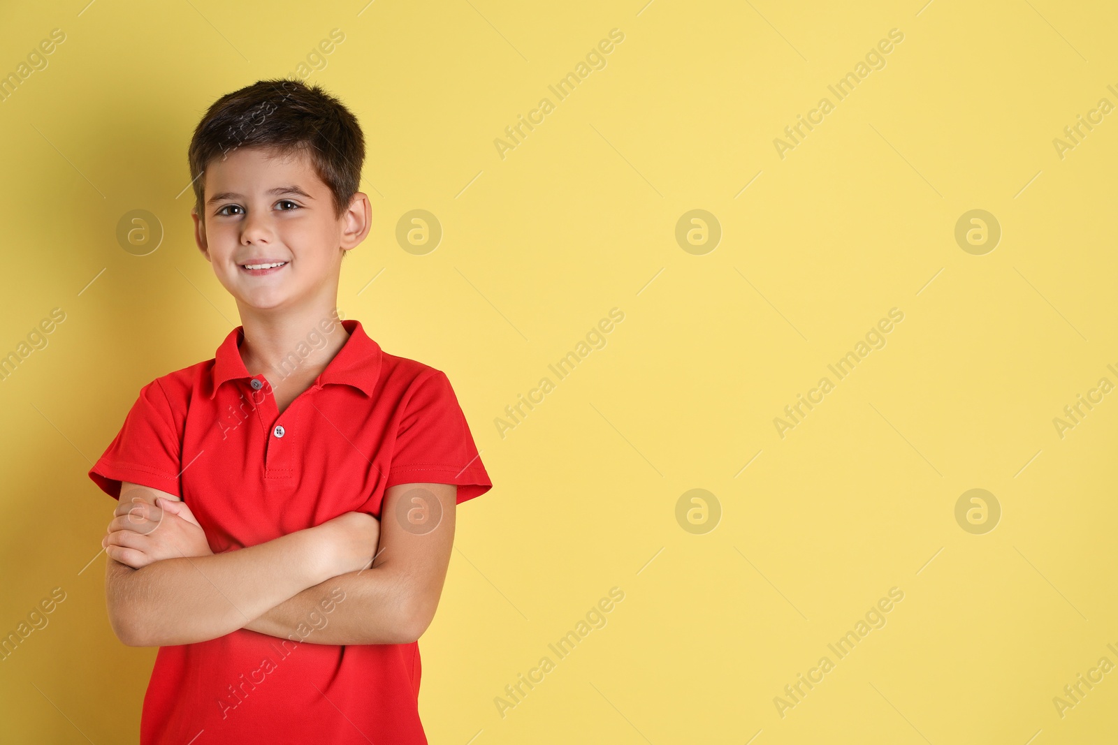 Photo of Portrait of cute little boy on yellow background, space for text