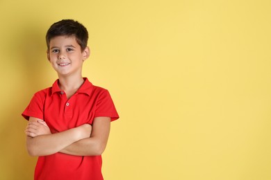 Portrait of cute little boy on yellow background, space for text